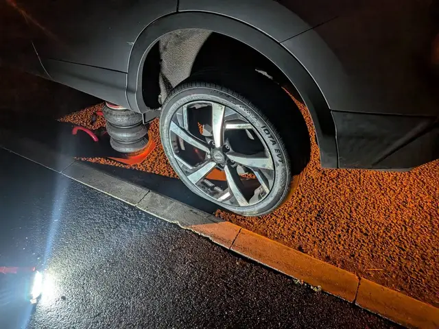A Nissan Qashqai on an air jack in a layby on the A1 near Long Bennington at night, new tyre fitted
