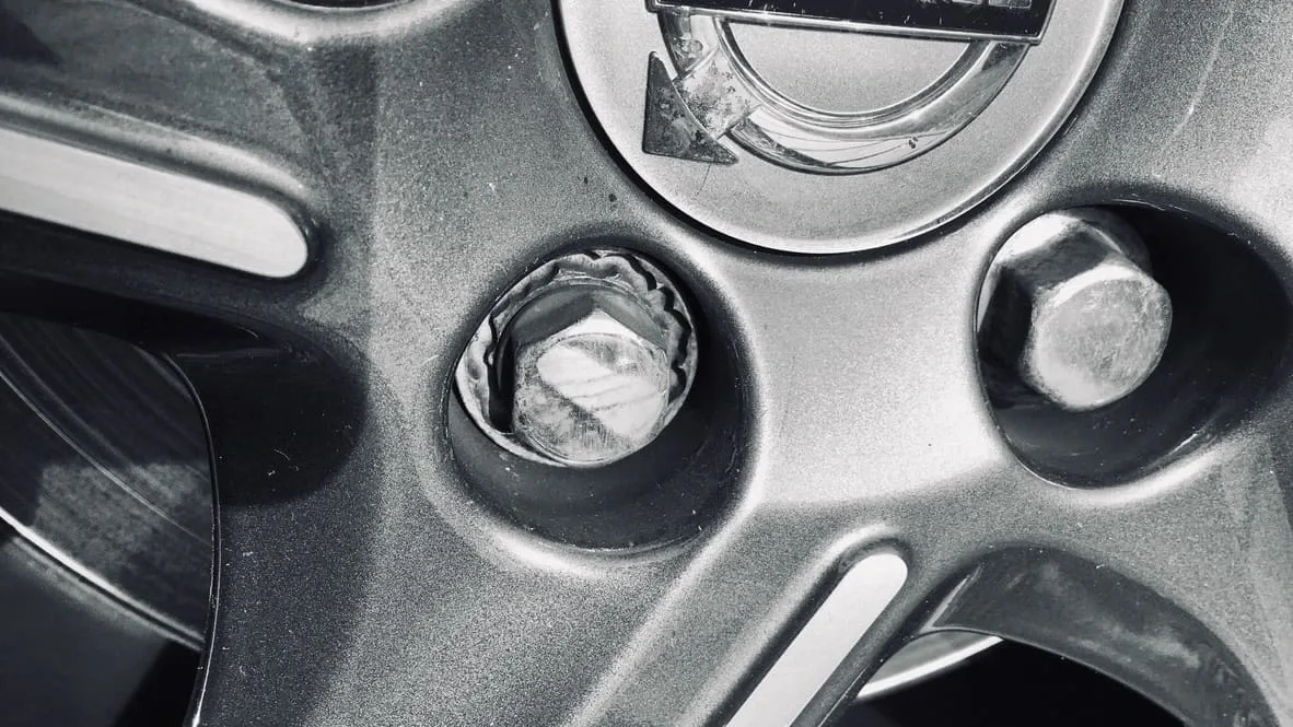 Close-up of a stripped locking wheel nut being extracted on an alloy wheel